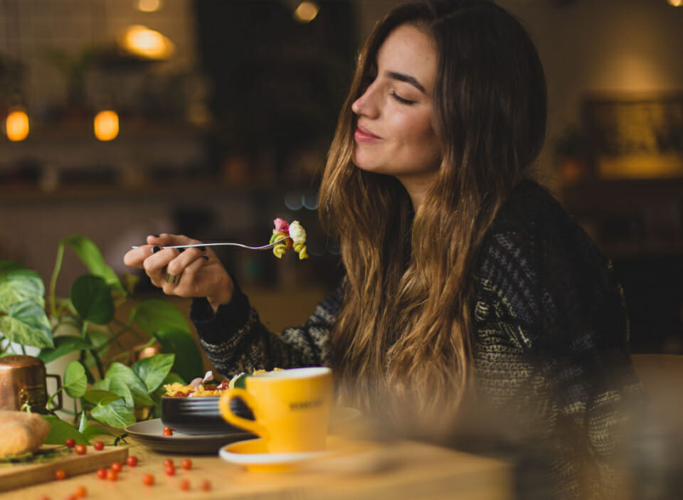 Woman enjoying pasta and a coffee ensuring she's getting some healthy food and foods that make you happy