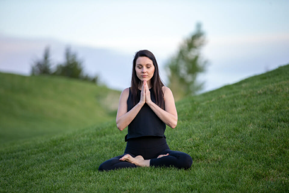 woman meditating outside on grass