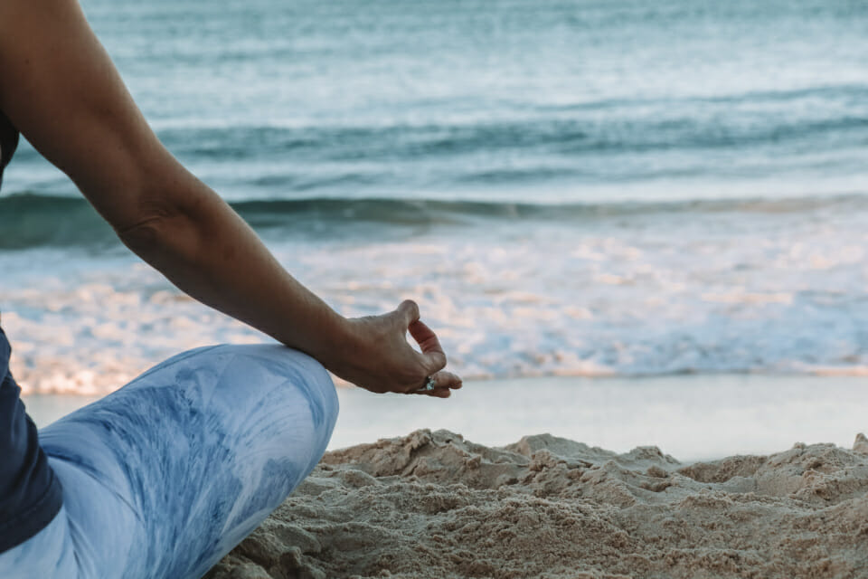 woman meditating on beach