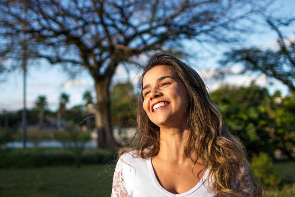 A smiling woman in a park happy to have eased her perimenopause or menopause symptoms