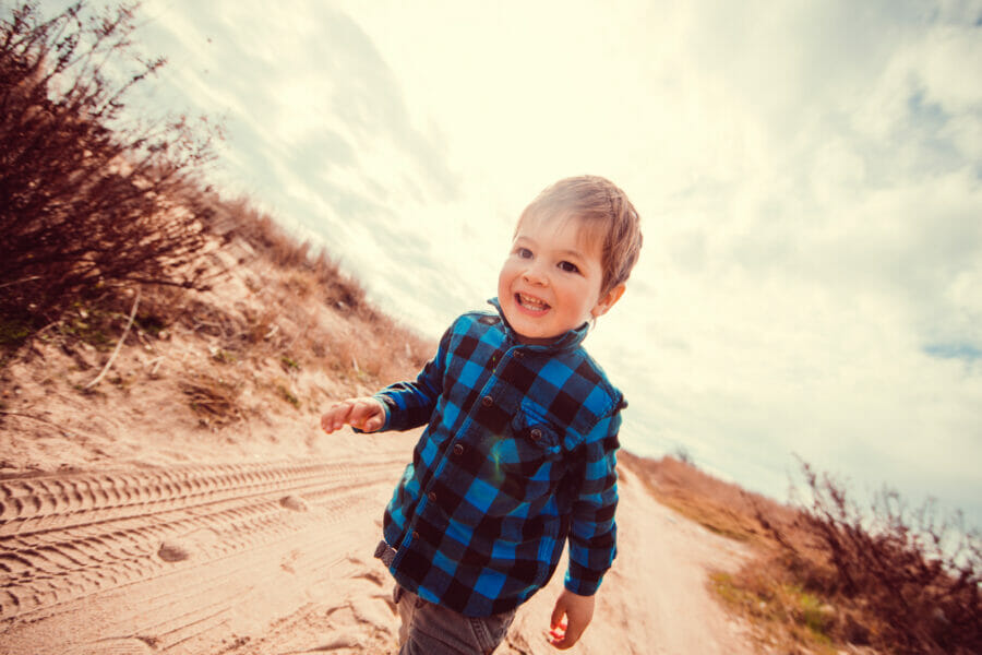 Photo of a little smiling boy spending sunny day in the nature