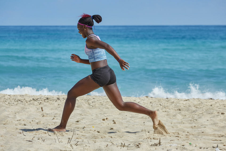 Black woman running on the beach in exercise gear