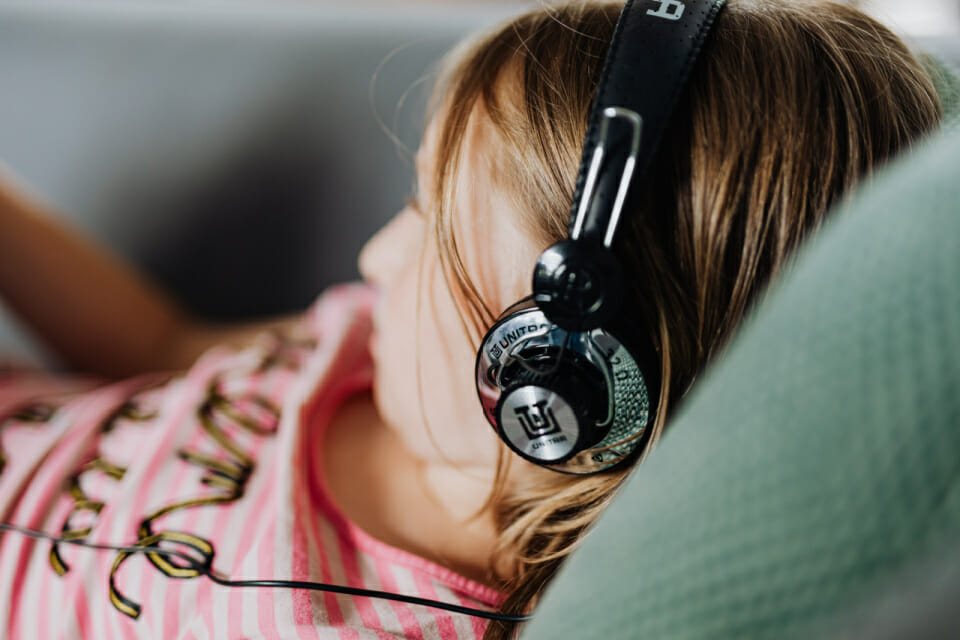 Young girl laying on the couch listening to music in big headphones