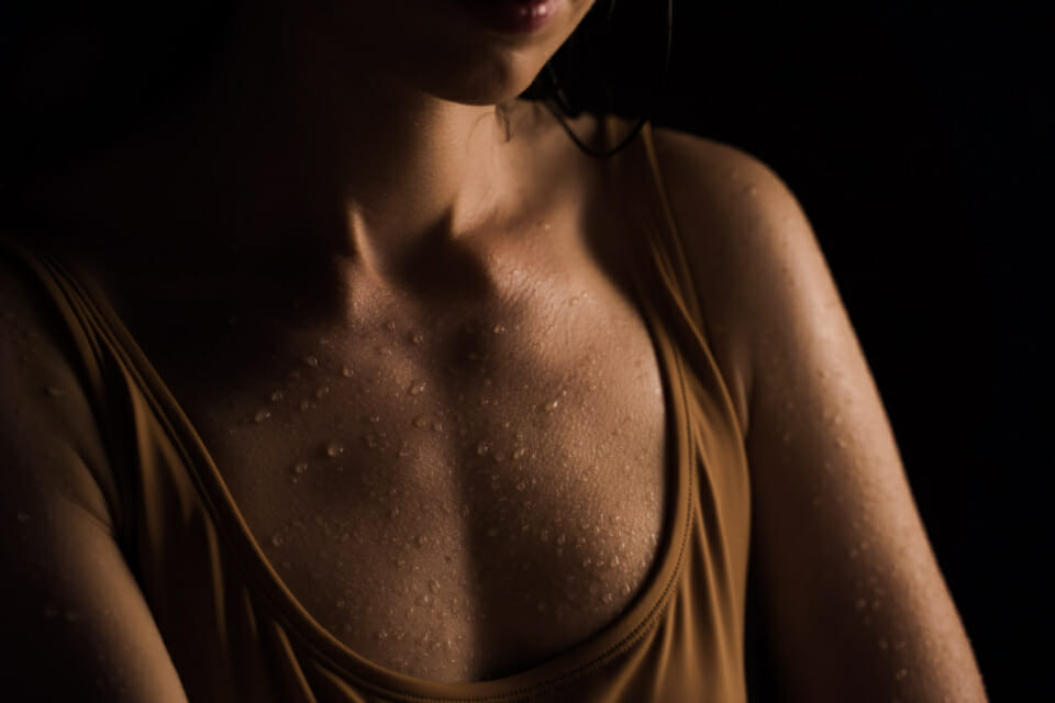 Woman's chest with sweat beads due to perimenopause or menopause symptoms