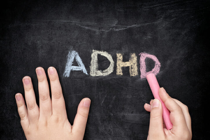 Child with ADHD writhing ADHD on a blackboard. ADHD is Attention deficit hyperactivity disorder.