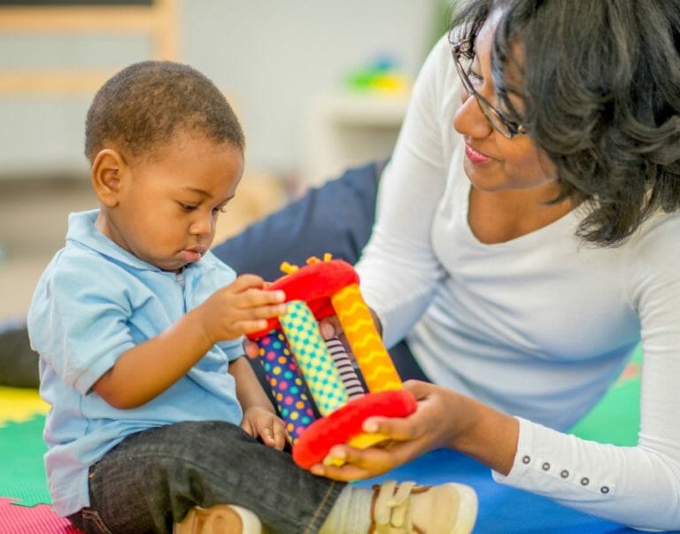 A black mother and her son play with engaging and educational toys suited to toddlers as a way to improve your kid's self-awareness