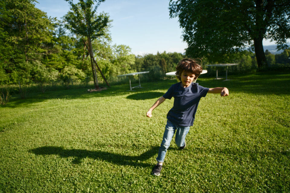 A young white boy running around on the grass to express some of his childhood ADHD symptoms