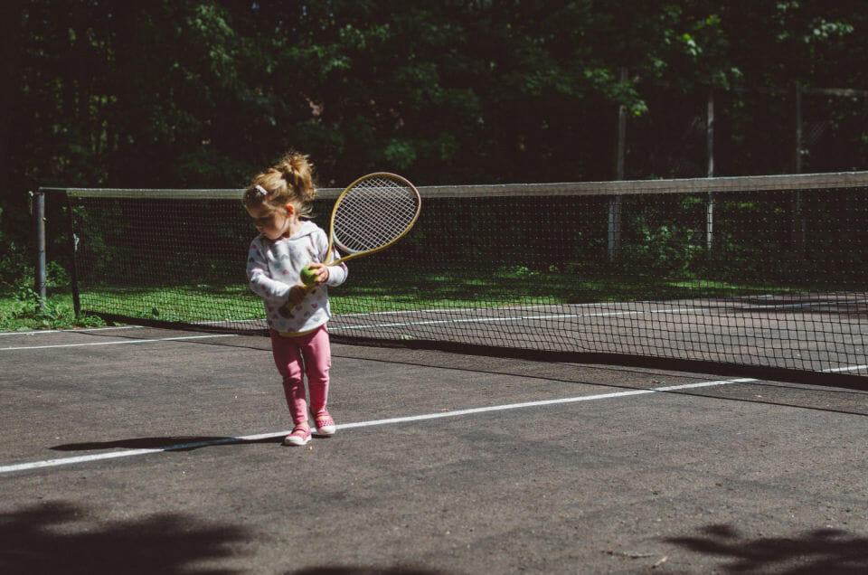 Child with ADHD playing tennis to express energy