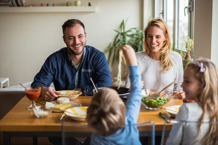 Image of a white nuclear family - mother, father, son, daughter - sitting down for dinner in order to reconnect as a family