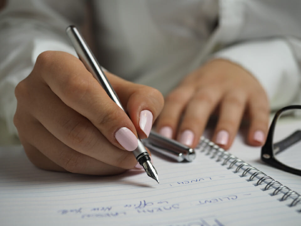 Taking in the good and practising gratitude - image of a hand writing in a notebook with a calligraphy pen