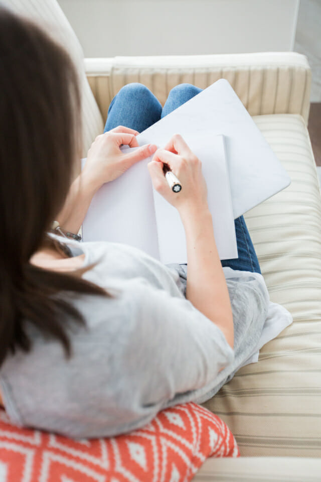 Image of a woman sitting on a couch journaling